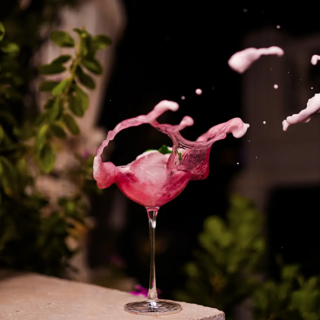 Pink cocktail splashing out of a glass in a dramatic freeze-frame shot at a Bangalore brewhouse.