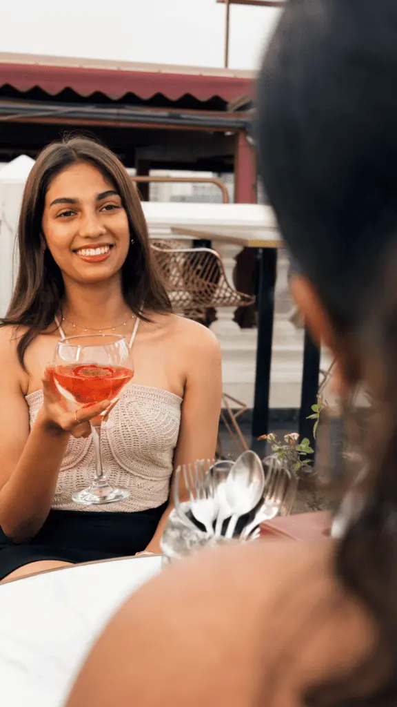 Woman smiling while holding a cocktail at an outdoor seating area of Candles Brewhouse.