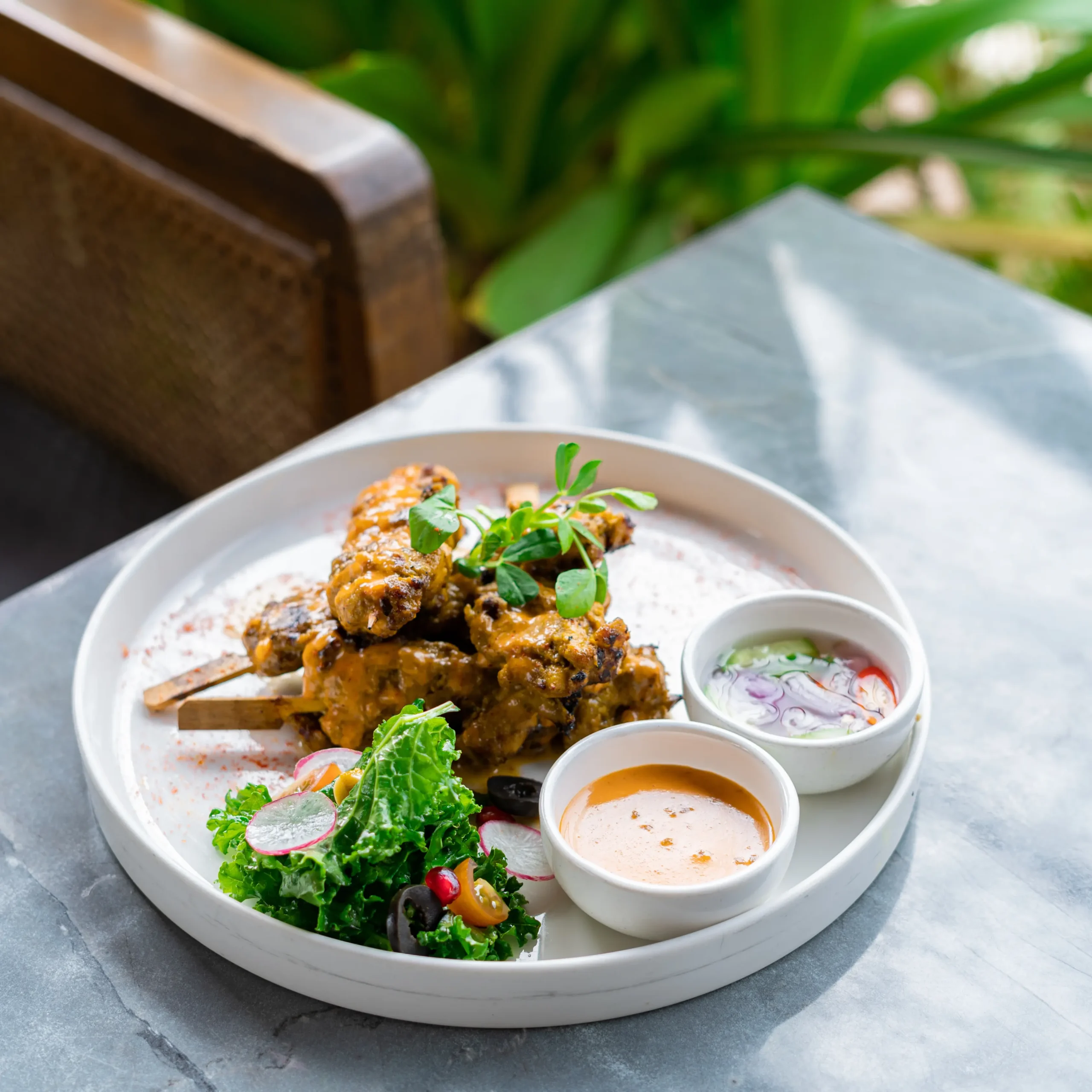 Grilled skewers served with fresh salad and two dipping sauces on a white plate at a Bangalore brewhouse.