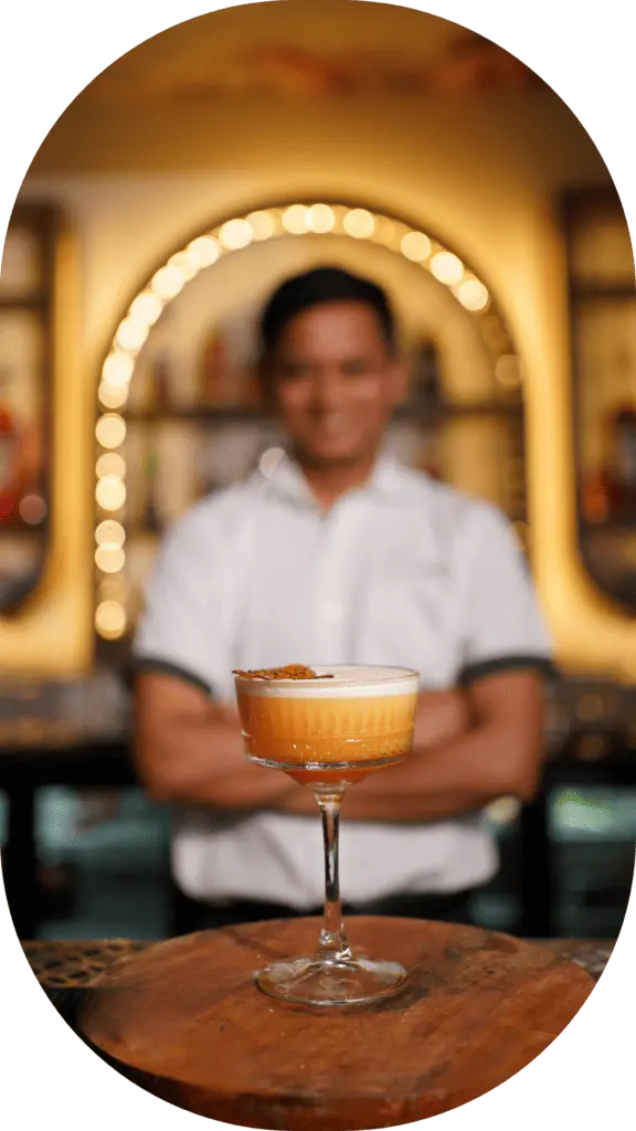 Signature cocktail placed on the counter with a bartender standing in the background at Candles Brewhouse.